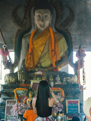 A woman making a wish from a buddha statue