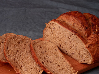 Sliced homemade bread on a cutting board in the kitchen on a wooden background.