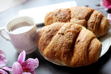 Cup of coffee, croissant and orchids