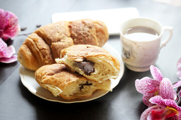 Cup of coffee, croissant and orchids