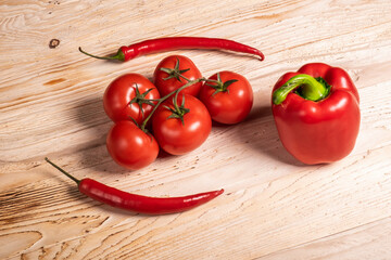 Juicy vegetables, bell peppers and chili peppers and tomatoes on a wooden table. Fresh vegetables on a branch. Kitchen. background for restaurant.