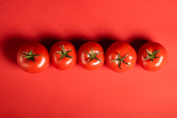 Juicy tomatoes on a bright red background. Fresh vegetables on a branch. Kitchen. background for restaurant.