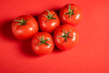 Juicy tomatoes on a bright red background. Fresh vegetables on a branch. Kitchen. background for restaurant.
