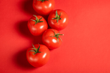 Juicy tomatoes on a bright red background. Fresh vegetables on a branch. Kitchen. background for restaurant.