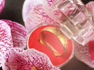 Wedding ring in a glass box and pink orchids