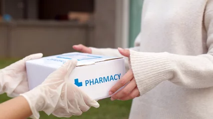 Papier Peint photo Lavable Pharmacie Asian female patient receive medication package box free first aid from pharmacy hospital delivery service at home wear glove in telehealth, telemedicine healthcare insurance online concept.