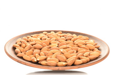 Several grains of peeled raw, organic almonds on a clay plate, close-up, isolated on white.