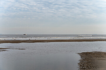 Low tide period on yellow sandy beach in small Belgian town De Haan or Le Coq sur mer, luxury vacation destination, summer holidays