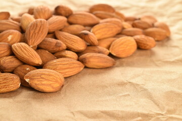 Several grains of peeled raw, organic almonds, close-up, on craft paper.