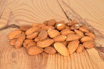 Several grains of peeled raw, organic almonds, close-up, on a wooden table.