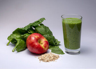 Green smoothie in glass with ingredients: spinach, apple and oat flakes. Studio isolated on white.