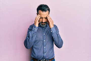 Middle age man with beard and grey hair wearing business clothes with hand on head for pain in head...
