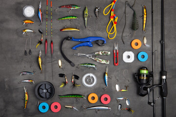 Fishing tackle - fishing spinning rod, hooks and lures on gray background. Active hobby recreation...