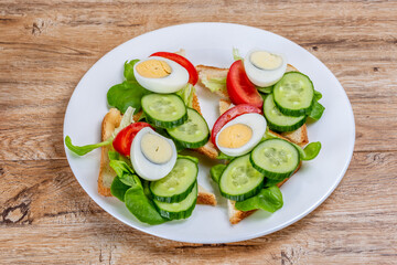 Fried white bread toasts with vegetable and egg slices on a plate
