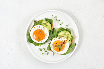 Fried eggs, avocado and greens on bread
