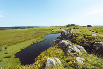 Fototapeta premium Northumberland UK: Hadrians Wall built on tall cliffs (Roman Wall) on a sunny summer day in English countryside. Lake view