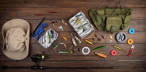 Fishing tackle - fishing spinning rod, hooks and lures on wooden background. Active hobby...
