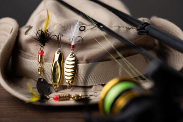 Fishing tackle - fishing spinning rod, hooks and lures on wooden background. Active hobby...