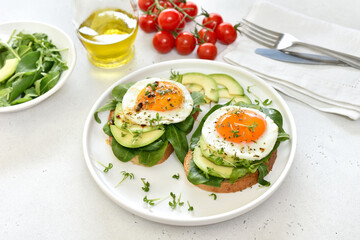 Fried eggs, avocado and greens on toasted bread