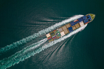 Aerial top view of cargo ship with contrail in the ocean sea ship carrying container and running...