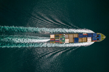 Aerial top view of cargo ship with contrail in the ocean sea ship carrying container and running...