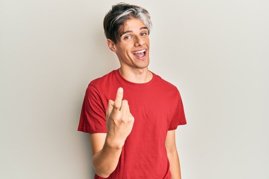 Young hispanic man wearing casual clothes beckoning come here gesture with hand inviting welcoming happy and smiling