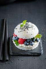 Delicious sush burger with blueberries and raspberries on stone plate.