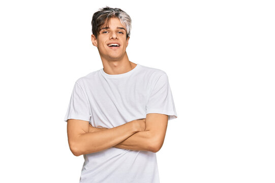 Young hispanic man wearing casual white tshirt happy face smiling with crossed arms looking at the camera. positive person.