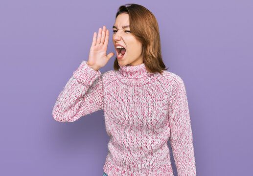 Young caucasian girl wearing wool winter sweater shouting and screaming loud to side with hand on mouth. communication concept.