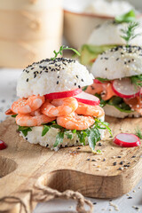 Tasty sush burger with seafood and vegetables sprinkled with sesame.