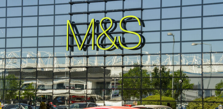 Cardiff, Wales - July 2018: Glass front of a branch of Marks and Spencer in Cardiff, with relfections of cars parked in front of the store.