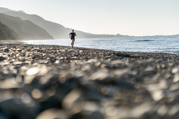 Man run on the beach, mountains background