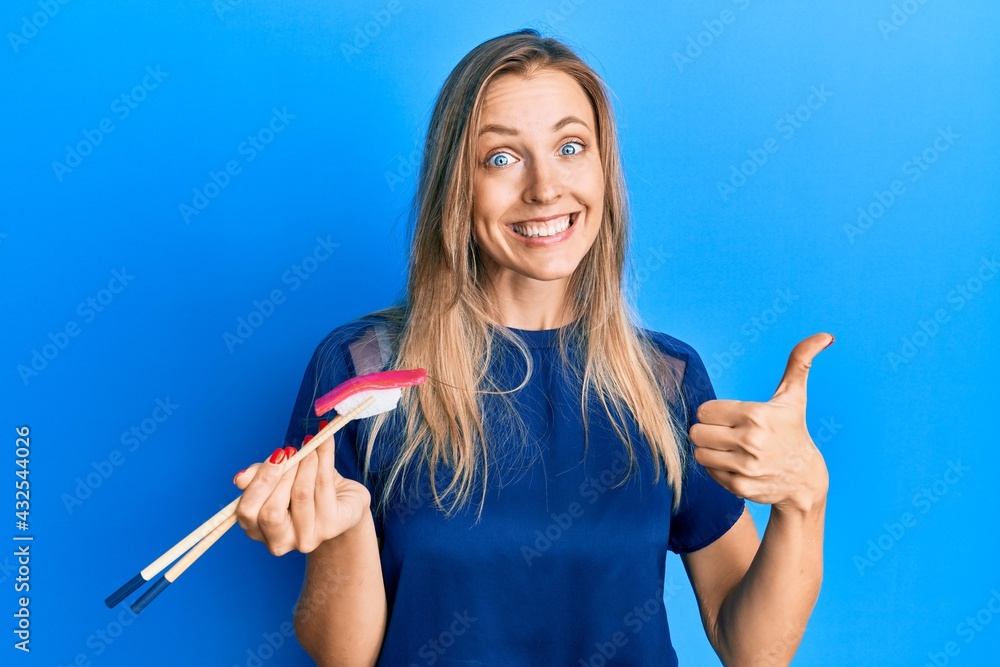 Sticker Beautiful caucasian woman eating nigiri sushi using chopsticks smiling happy and positive, thumb up doing excellent and approval sign