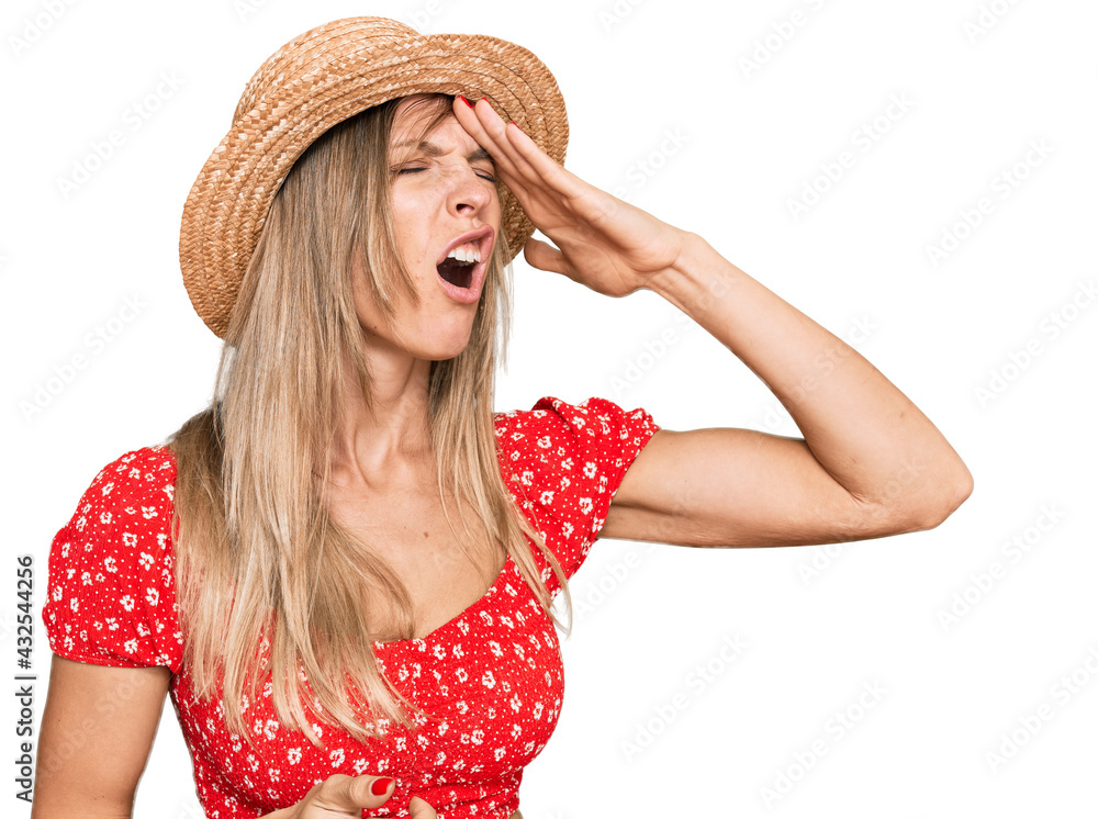 Poster beautiful caucasian woman wearing summer hat surprised with hand on head for mistake, remember error