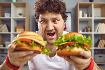 Funny fat guy eating fast food. Happy athlete enjoying delicious burgers on cheat day. Chubby man...