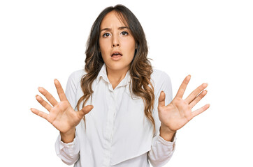 Young brunette woman wearing casual clothes afraid and terrified with fear expression stop gesture with hands, shouting in shock. panic concept.