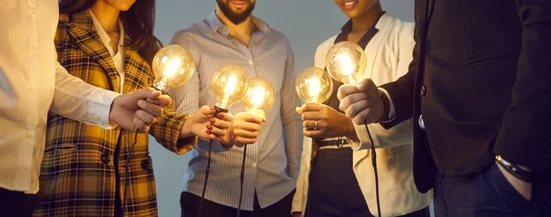 Foto auf Acrylglas Background with young multiethnic business team holding glowing vintage Edison lightbulbs. Multiracial men and women join shining electric light bulbs for teamwork and sharing creative ideas © Studio Romantic