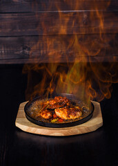 fajitos, meat in a frying pan with fire on a wooden tray, beautiful serving, dark background