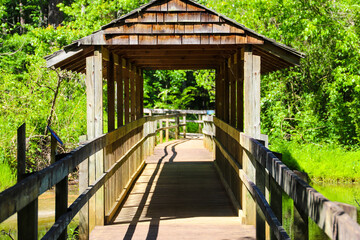 a long winding brown wooden bridge with a cover over the top in the forest over the water in the...