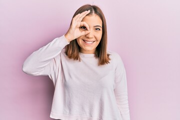 Young beautiful woman wearing casual clothes smiling happy doing ok sign with hand on eye looking through fingers