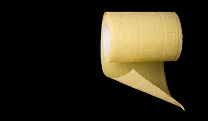 Roll of yellow toilet paper on black background close up