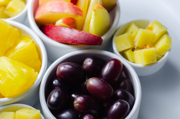 Various set fruits, pineapple, apple, grapes with matured cheddar cheese in bowls