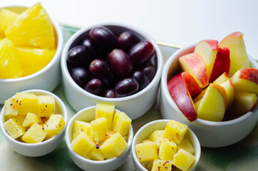 Various set fruits, pineapple, apple, grapes with matured cheddar cheese in bowls