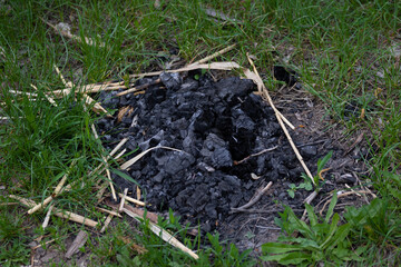 Coals and ashes left over from a campfire illegally bred in the woods on the grass during the warm summer season of the outdoor bonfire on a outdoor holiday. High quality photo