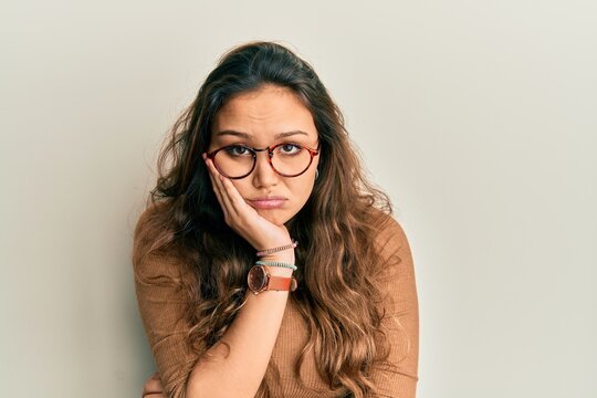 Young hispanic girl wearing casual clothes and glasses thinking looking tired and bored with depression problems with crossed arms.