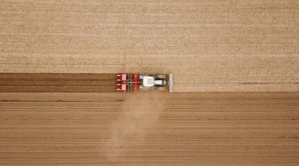 Traktor mit Sämaschine wirbelt bei der Aussaat von Mais Staub auf einem Acker auf, Landwirtschaft,...