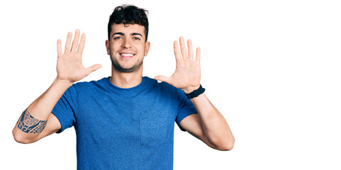 Young hispanic man wearing casual t shirt showing and pointing up with fingers number ten while smiling confident and happy.