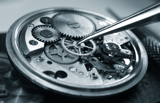vintage watch under repair, display of parts of vintage watch mechanism: dial, gears, screws, balance wheel and springs