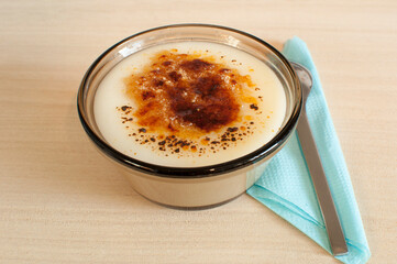 Glass plate with dessert. Rice pudding, on a white plate with a napkin and a spoon.