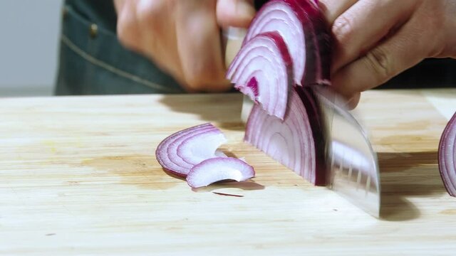 Chef cut the onions, cuts onion close-up, Chopping onion - slow motion, clears bulb onions with knife on background wooden Board